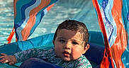 Santiago is registered to the contest to win money with this photo: baby, blue, child, colorful, float, infant, orange, outdoor, play, pool, relax, splash, summer, sunlight, sunshade, swimming, swimwear, water, waves, wet_hair