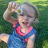 Paisley is registered to the contest to win money with this photo: child, toddler, flower, daisy, grass, outdoor, sunlight, denim_overalls, pink_shirt, nature, playful, curious, greenery, summer, sitting, person, young_child, happy, casual_clothing, daylight