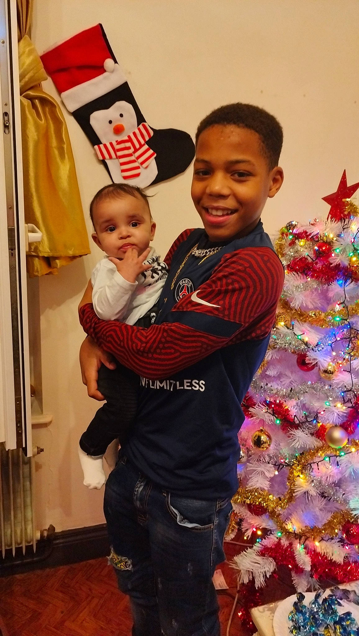 Samir participe au concours pour gagner de l'argent avec cette photo : belt, child, christmas, christmas_ornament, christmas_tree, event, fun, gesture, happy, holiday, holiday_ornament, joy, ornament, person, room, sleeve, smile, standing, t_shirt, toddler