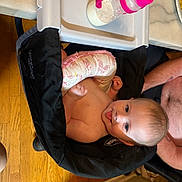 Olive joined the competition — help win amazing prizes! baby, child, high_chair, bottle, milk, tongue_out, pillow, black_fabric, wood_floor, marble_countertop, arm, shirtless, cute, happy, indoor, feeding, infant, person, table, kitchen