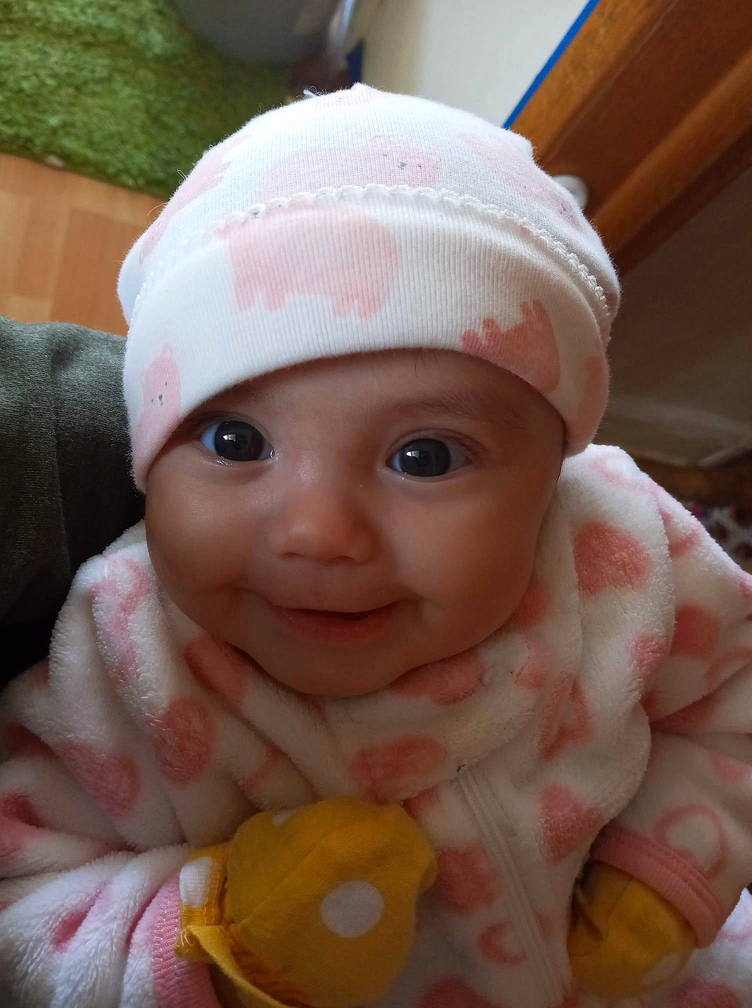 Anahi is registered to the contest to win money with this photo: baby, cap, cheek, child, close_up, creative_arts, eye, fashion_accessory, finger, hand, headgear, headwear, knit_cap, lip, nose, person, pink, skin, smile, toddler