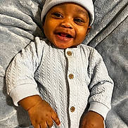 Kenai joined the competition — help win amazing prizes! baby, smiling, infant, blue_hat, knitted_outfit, blanket, soft_texture, happy, cute, child, portrait, indoors, warm_clothing, hands, face, buttoned_outfit, lying_down, cozy, newborn, expressive