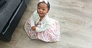 A'Myah joined the competition — help win amazing prizes! bow, cardigan, casual, child, couch, cute, dress, floor, furniture, girl, hair_bow, happy, indoor, playful, sitting, small_child, smiling, toddler, white_shoe, wooden_floor