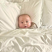 Nathaniel joined the competition — help win amazing prizes! baby, blanket, pillow, bed, child, face, infant, cozy, white, soft, comfort, rest, indoors, sleepwear, cute, portrait, lying_down, skin, head, expression
