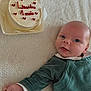 baby, infant, cake, celebration, milestone, blanket, green_clothing, cute, face, portrait, lying_down, hand, head, eyes, mouth, white_background, food, dessert, red_icing, one_month