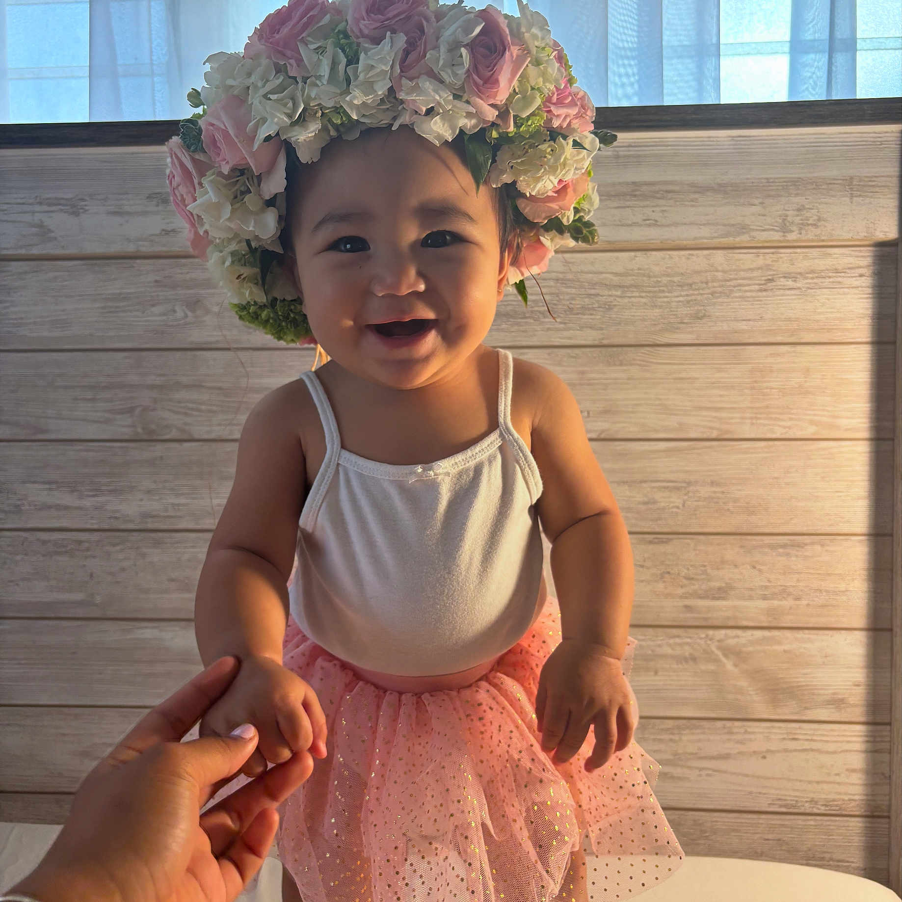 Kyrie Lynn joined the competition — help win amazing prizes! baby, child, cute, flower_crown, happy, headwear, holding_hand, human_hand, indoor, infant, person, pink_tutu, portrait, skin, smiling, soft_lighting, sparkle, tulle, white_top, wooden_background