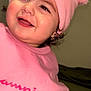 toddler, child, pink_hat, pom_poms, pink_sweatshirt, smiling, happy, face, portrait, indoors, clothing, cute, young_child, person, headwear, warm_clothing, casual, close_up, eyelashes, cheeks
