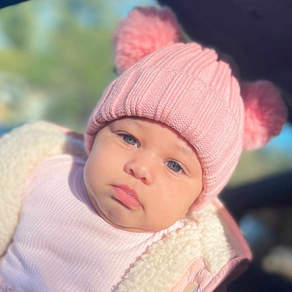 Azariah is registered to the contest to win money with this photo: baby, beanie, bonnet, cap, clothing, face, hat, head, knitwear, person, sad, sweater