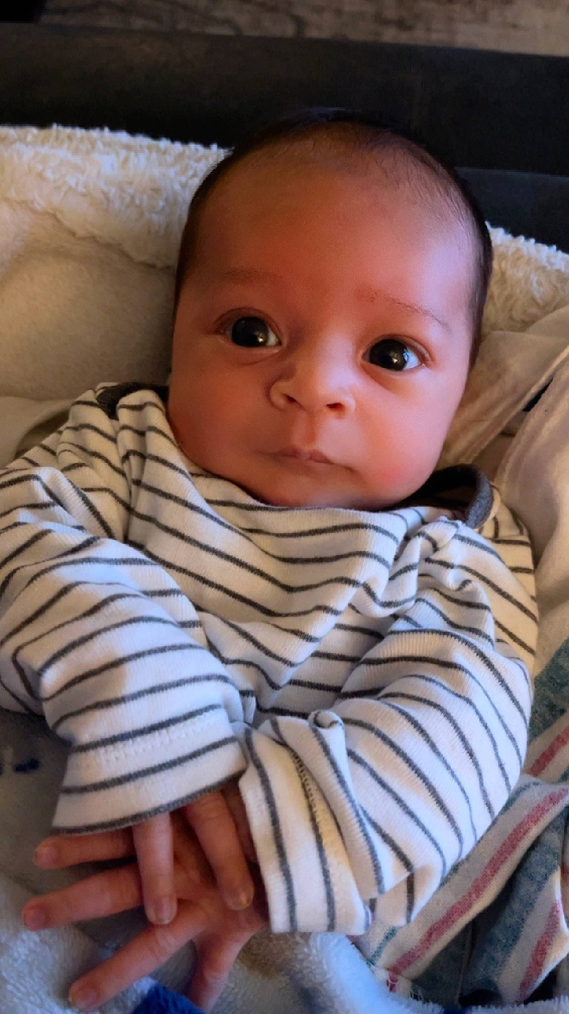 Kai is registered to the contest to win money with this photo: baby, baby_toddler_clothing, cheek, child, chin, comfort, eye, fur, iris, linens, nose, pattern, person, sitting, skin, sleeve, toddler, wood