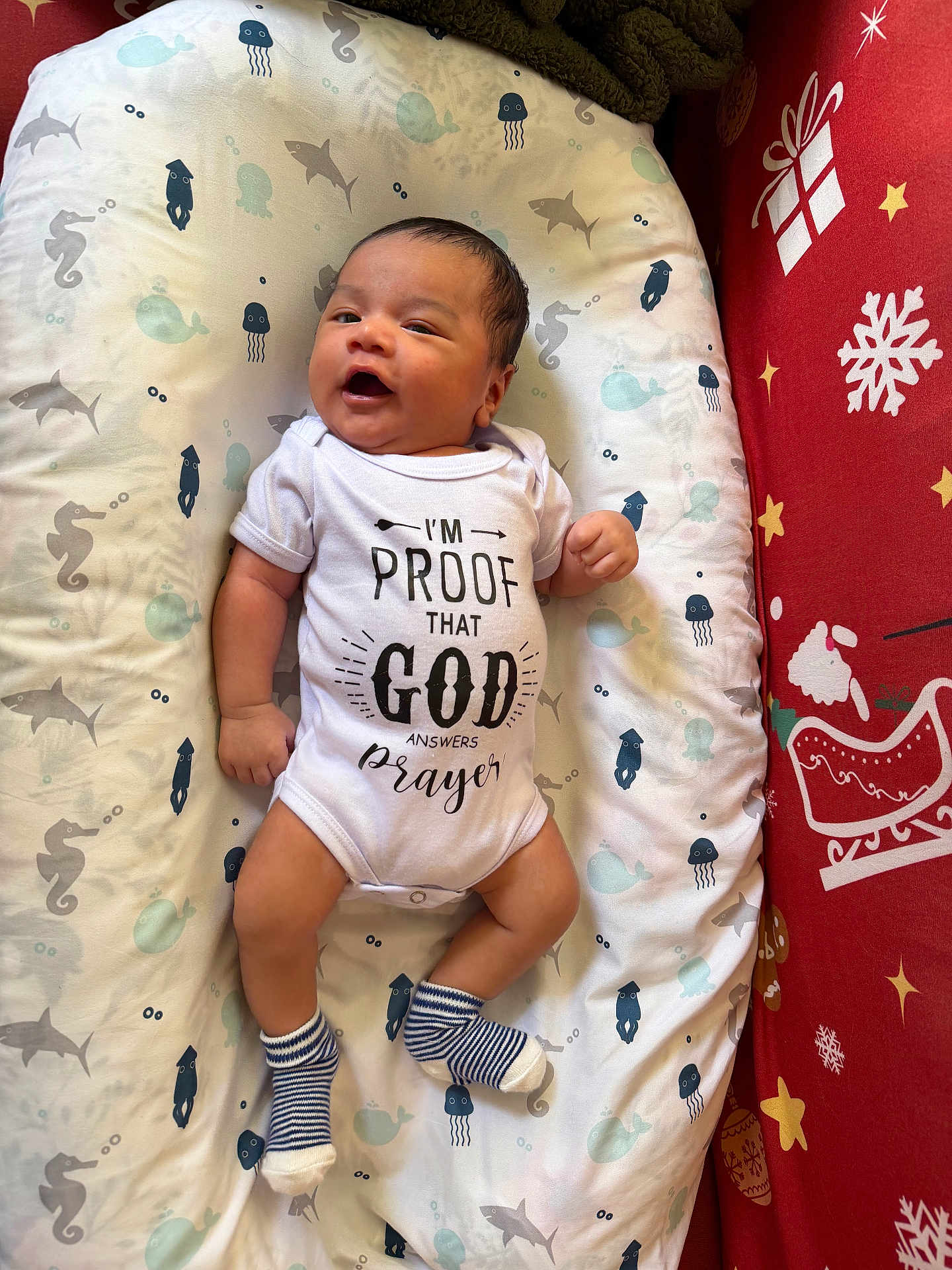 Nathan joined the competition — help win amazing prizes! baby, infant, onesie, socks, smiling, face, cushion, sea_creatures, sharks, seahorses, jellyfish, whales, blanket, bed, christmas, holiday, red, white, person, happy