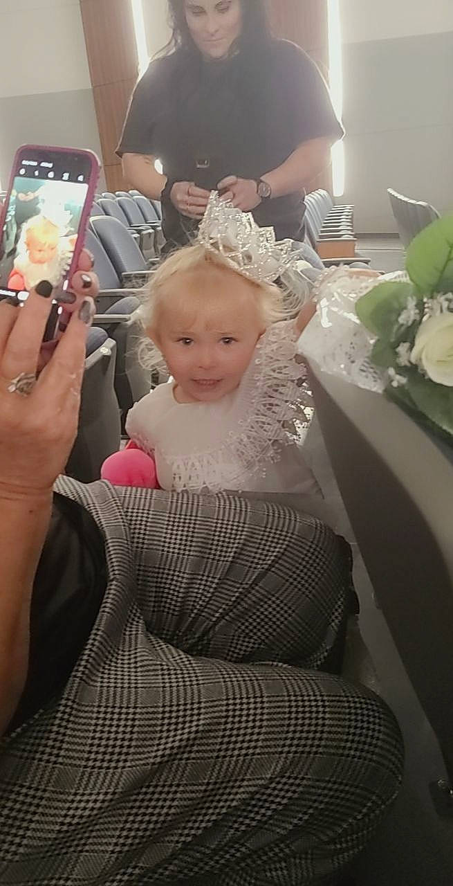 Davina is registered to the contest to win money with this photo: baby, bridal_clothing, chair, communication_device, dress, event, finger, formal_wear, fun, gadget, gown, happy, mobile_phone, person, portable_communications_device, selfie, sitting, skin, suit, telephony