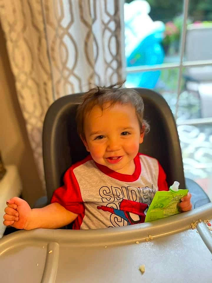 Lincoln is registered to the contest to win money with this photo: baby, baby_toddler_clothing, cheek, child, comfort, curtain, finger, fun, happy, joy, leisure, person, room, sitting, skin, sleeve, smile, t_shirt, table, tableware