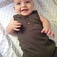 Max joined the competition — help win amazing prizes! baby, smiling, infant, star_pattern, mattress, brown_outfit, sleeveless, cute, child, happy, lying_down, indoor, person, skin, hand, face, head, eyes, mouth, fingers