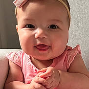 Gianna is registered to the contest to win money with this photo: baby, child, pink_outfit, headband, bow, smiling, tongue_out, hands_clasped, sitting, indoor, chair, cute, happy, infant, portrait, chubby_cheeks, natural_light, clothing, person, young_child