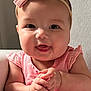 baby, child, pink_outfit, headband, bow, smiling, tongue_out, hands_clasped, sitting, indoor, chair, cute, happy, infant, portrait, chubby_cheeks, natural_light, clothing, person, young_child