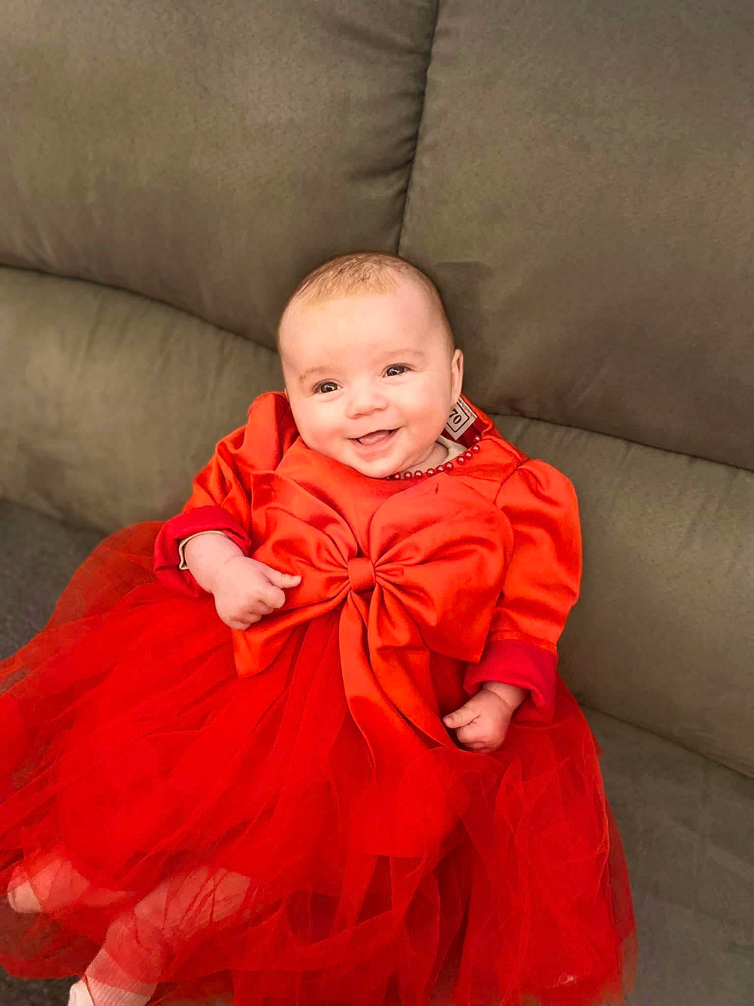 Kellyana participe au concours pour gagner de l'argent avec cette photo : baby, baby_toddler_clothing, child, comfort, couch, dress, event, flooring, formal_wear, fun, happy, joy, magenta, orange, peach, person, room, sleeve, smile, textile