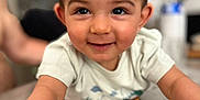 Lyham participe au concours pour gagner de l'argent avec cette photo : child, toddler, smiling, face, eyes, arm, table, wood, indoors, person, cute, happy, skin, hair, white_shirt, expression, baby, closeup, portrait, blurred_background