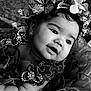 baby, child, portrait, black_and_white, flower_crown, dress, sparkles, cute, face, earrings, soft_lighting, closeup, infant, adorable, smile, decorative, fabric, young_child, expression, headshot