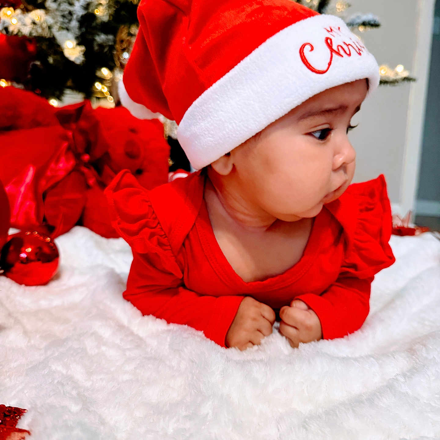 Naisha joined the competition — help win amazing prizes! baby, blanket, celebration, child, christmas, christmas_tree, cute, decorations, face, festive, holiday, holiday_lighting, indoors, infant, red_clothing, santa_hat, smiling, soft_texture, toddler, winter