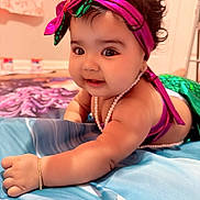 Naisha is registered to the contest to win money with this photo: baby, blanket, bracelet, child, closeup, costume, curly_hair, cute, happy, headband, indoor, infant, lying_down, mermaid_costume, pearl_necklace, person, playful, portrait, smiling, toddler