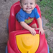 Alvin is registered to the contest to win money with this photo: child, toddler, smiling, toy_car, outdoor, grass, concrete, red, yellow, blue, shorts, shirt, happy, person, play, summer, cute, kid, hands, face