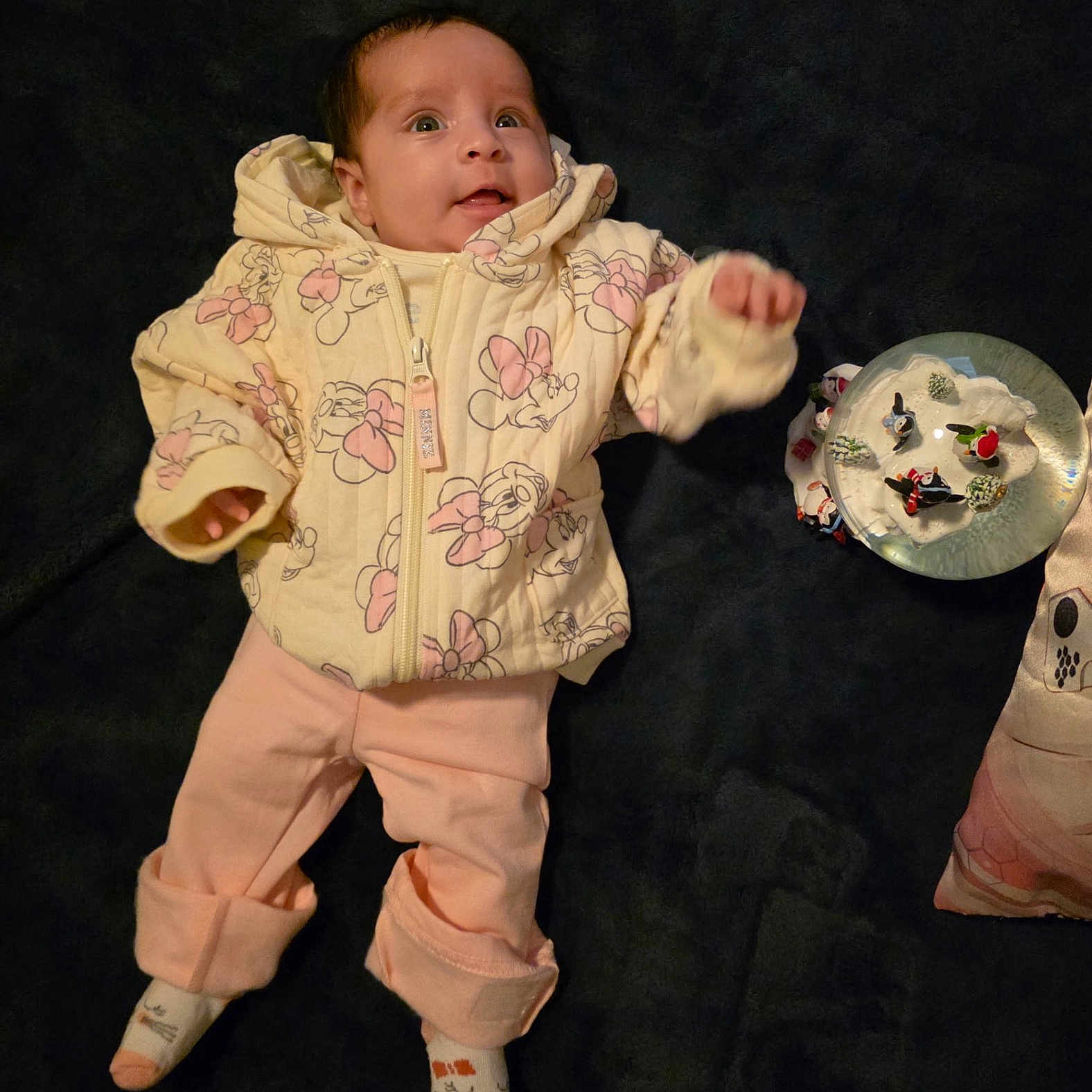 Mariah Recendez is registered to the contest to win money with this photo: baby, blanket, child, clothing, curious, cute, decor, expression, face, indoor, infant, jacket, lying_down, pants, person, pink, snow_globe, socks, toy, yellow