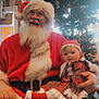Rhaelynn is registered to the contest to win money with this photo: santa_claus, baby, christmas_tree, holiday, festive_clothing, plaid_dress, lace, red_suit, beard, glasses, hat, indoor, celebration, smiling, decorations, lights, festive, person, child, christmas