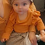 Rhaelynn is registered to the contest to win money with this photo: baby, child, person, orange_clothing, hat, checkered_skirt, sitting, indoor, human, cute, smiling, face, hand, lap, portrait, bright_eyes, apparel, fashion, young, infant
