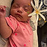 baby, sleeping, pink_onesie, heart_pattern, flower, cushion, indoor, infant, peaceful, resting, child, portrait, closeup, cute, soft_lighting, relaxing, young_child, face, hand, skin