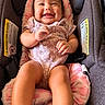 baby, infant, child, smiling, happy, portrait, car_seat, safety_harness, pink_outfit, blanket, seated, indoor, close_up, face, eyes, hands, legs, floral_pattern, vehicle_interior,  안전