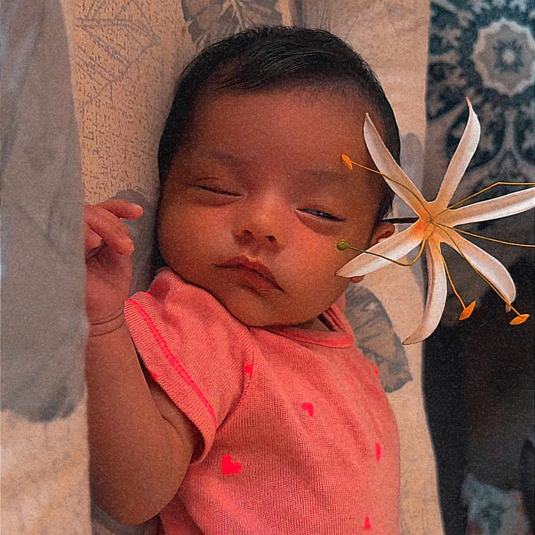 Priyah joined the competition — help win amazing prizes! baby, sleeping, pink_clothing, flower, cushion, patterned_fabric, infant, peaceful, indoors, closeup, newborn, soft_lighting, portrait, resting, cute, child, human, cozy, toddler, relaxed