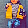 baby, child, infant, smiling, yellow_vest, striped_shirt, jeans, socks, couch, gray_fabric, indoor, portrait, cute, happy, person, young_child, seated, casual_clothing, relaxed, home