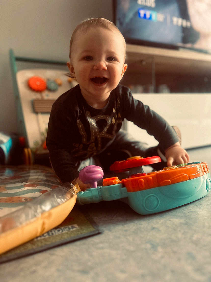 Tylio a rejoint le concours — aidez-le/la à gagner de superbes lots ! toddler, child, toy, smiling, indoor, floor, playing, happy, colorful, plastic_toy, person, casual_clothing, young_child, home, entertainment, cute, fun, joy, expression, baby