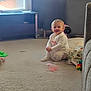 Alisha is registered to the contest to win money with this photo: toddler, child, carpet, toy, blanket, living_room, window, smile, sitting, furniture, couch, floor, indoor, clothing, person, home, light, soft, happy, cute