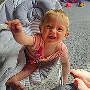 Alisha is registered to the contest to win money with this photo: baby, blanket, carpet, child, colorful, comfortable, cute, expression, foot, furniture, happy, home, indoor, infant, person, playroom, reaching, seat, smiling, toy