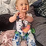 baby, blanket, child, clothing, colorful, cushion, cute, floral_wallpaper, happy, home, indoor, infant, keys, patterned_pants, person, playful, sitting, smiling, toy, young_child