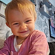 Alisha joined the competition — help win amazing prizes! toddler, child, smiling, pink_cardigan, indoor, living_room, wallpaper, shelves, decorations, face, happy, cute, playful, person, home, young_child, blond_hair, portrait, cozy, candid