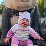 baby, child, panda_statue, outdoor, smiling, knitted_hat, pink_clothing, white_clothing, boots, sitting, happy, cute, statue, playful, daylight, photography, face, person, funny, nature