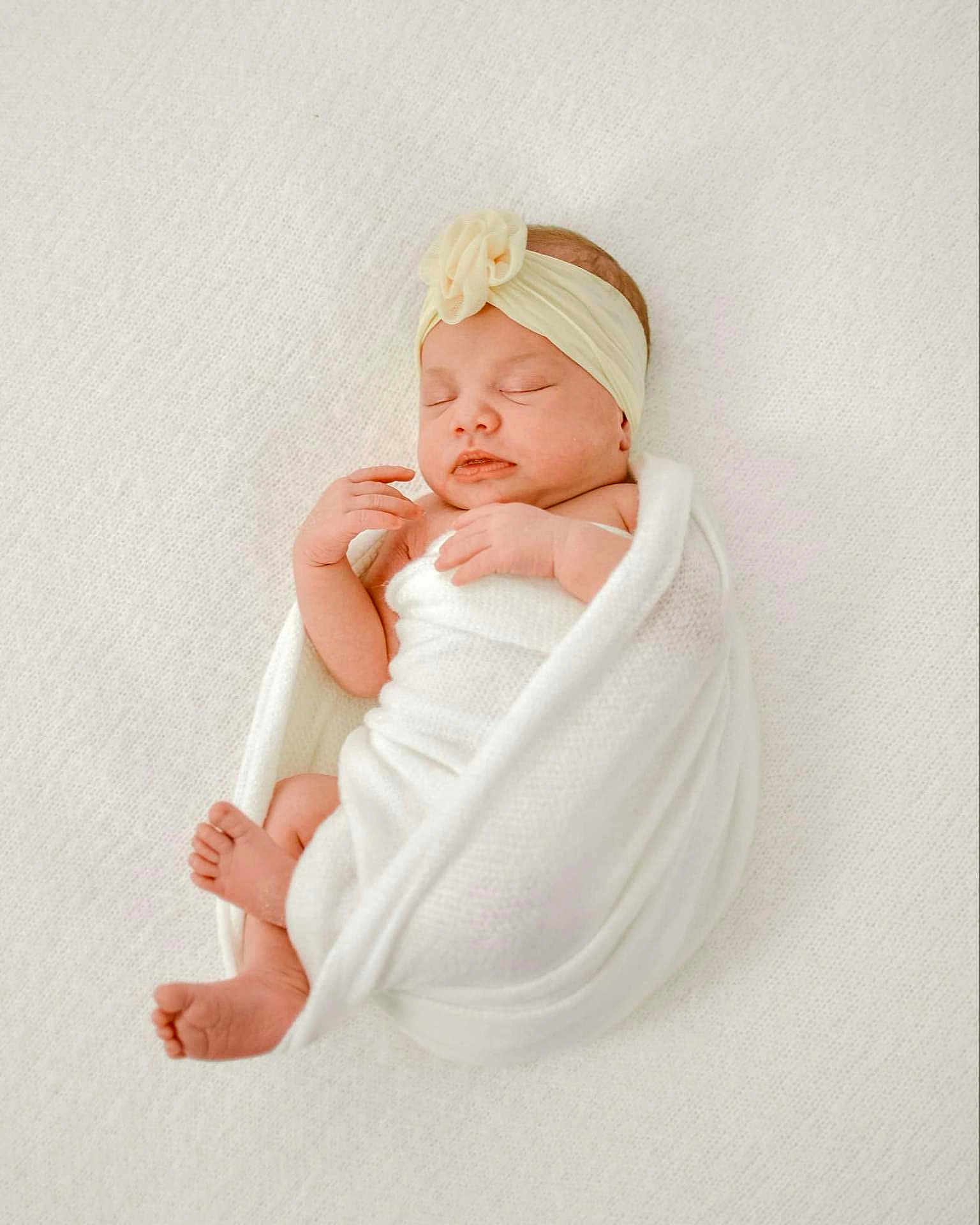 Roselie is registered to the contest to win money with this photo: newborn, baby, infant, sleeping, wrapped, blanket, headband, flower, white, soft, peaceful, cute, skin, feet, hands, portrait, indoors, closeup, resting, cozy