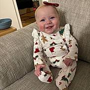 Olivia is registered to the contest to win money with this photo: baby, child, smile, holiday_pajamas, red_bow, headband, couch, indoor, drool, happy, infant, person, clothing, footed_pajamas, gingerbread, christmas, stockings, candy_canes, cozy, portrait