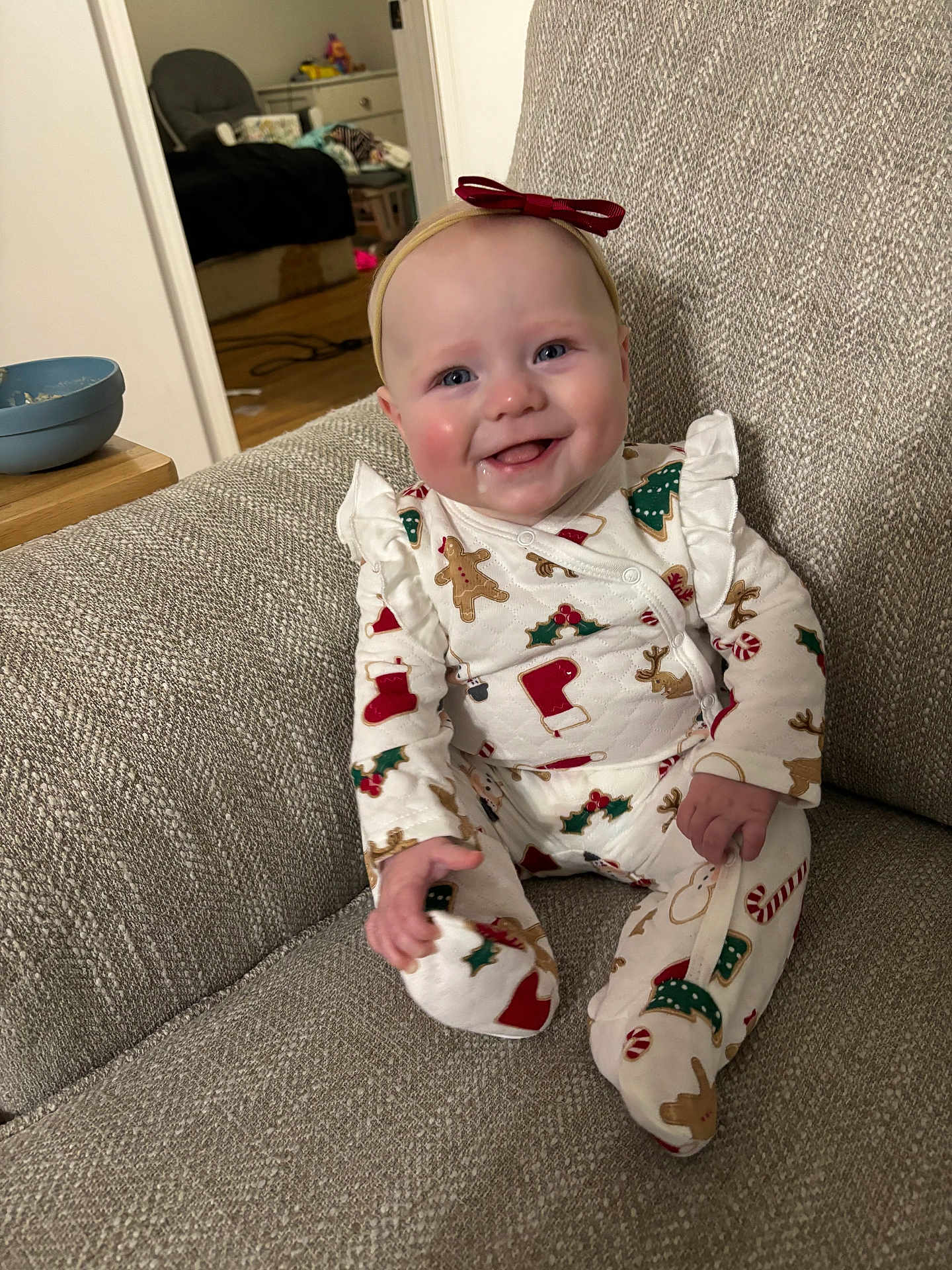 Olivia is registered to the contest to win money with this photo: baby, child, smile, holiday_pajamas, red_bow, headband, couch, indoor, drool, happy, infant, person, clothing, footed_pajamas, gingerbread, christmas, stockings, candy_canes, cozy, portrait
