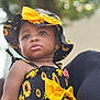 baby, bow, child, clothing, cute, dress, earring, face, fashion, hat, holding, nature, outdoor, pattern, person, portrait, skin, summer, sunflower, toddler