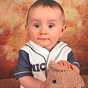 Zayden is registered to the contest to win money with this photo: baby, child, teddy_bear, plush_toy, portrait, cute, smiling, indoor, studio, clothing, short_hair, face, person, sitting, background, soft_light, toy, expression, young, warm_colors