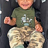 toddler, child, car_seat, smiling, green_shirt, camouflage_pants, socks, toy, indoors, happy, face, person, seatbelt, baby, cute, bright_eyes, playful, jungle_animals, clothing, portrait