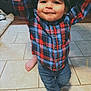baby, backwards_cap, boy, cap, celebration, child, cute, footwear, hand_holding, happy, home, indoor, jeans, person, plaid_shirt, smiling, support, tile_floor, toddler, walking