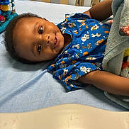 Javelle joined the competition — help win amazing prizes! baby, smiling, crib, blanket, blue_clothing, onesie, toy, nursery, infant, child, face, happy, lying_down, bed, furniture, patterned_clothing, arm, head, indoor, cozy