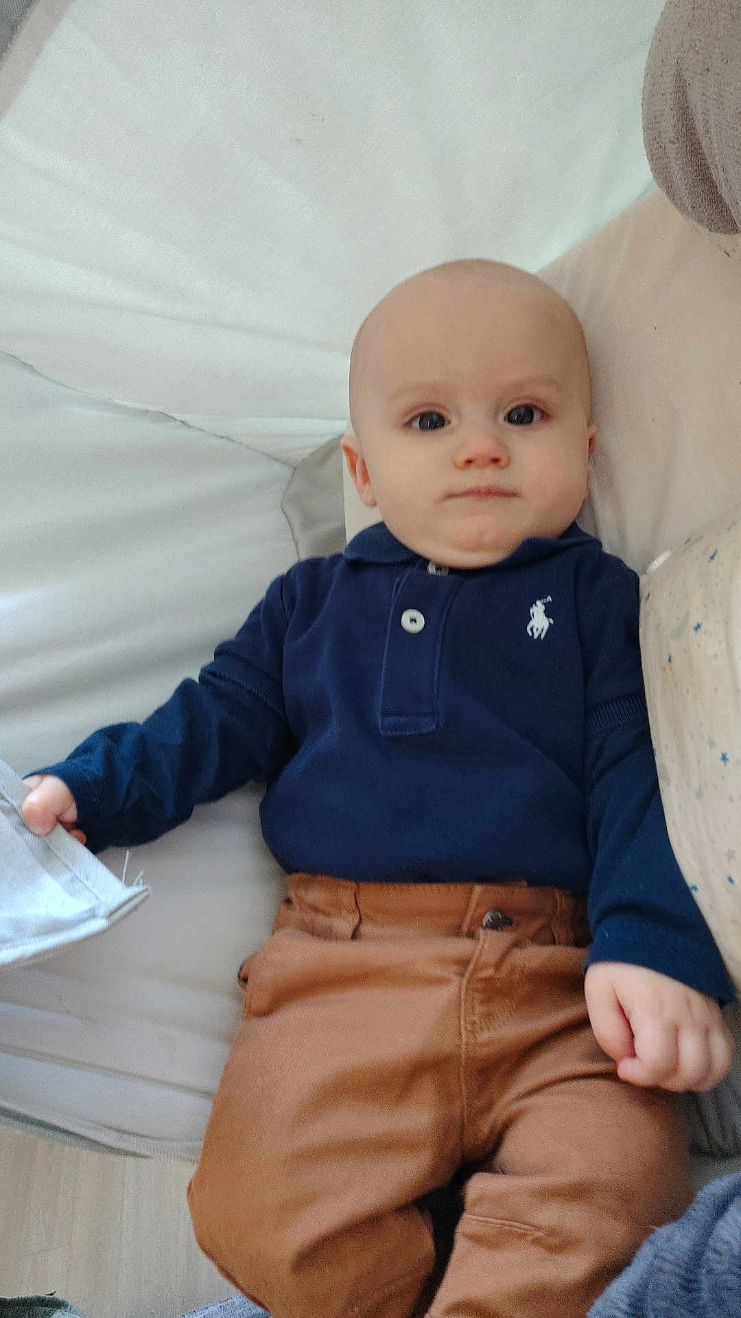 Alèzïo participe au concours pour gagner de l'argent avec cette photo : baby, child, infant, face, clothing, pants, long_sleeve, polo_shirt, couch, furniture, indoor, person, casual, light, skin, hand, relaxed, seated, young, portrait