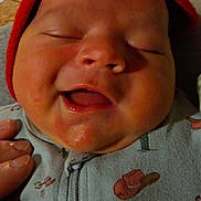 Oliver is registered to the contest to win money with this photo: baby, infant, smile, red_cap, close_up, hand, onesie, clothing, face, cheeks, mouth_open, sleepy_eyes, indoor, soft_lighting, newborn, cute, child, person, happy, portrait