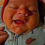 baby, infant, smile, red_cap, close_up, hand, onesie, clothing, face, cheeks, mouth_open, sleepy_eyes, indoor, soft_lighting, newborn, cute, child, person, happy, portrait