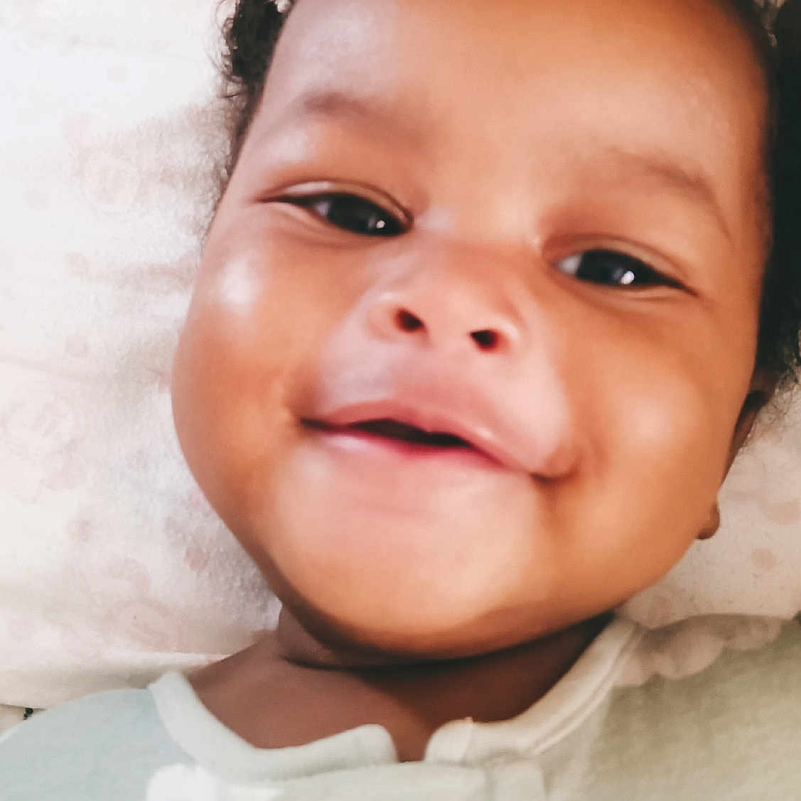 Chaanayah joined the competition — help win amazing prizes! baby, babywear, child, closeup, clothing, cute, expression, face, happy, head, indoors, infant, onesie, person, pillow, portrait, skin, sleepwear, smiling, young